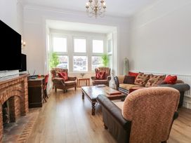 A living room with two armchairs, a sofa, a coffee table, a fireplace, and a desk by the window at The Burleigh in Hunstanton