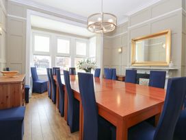 A dining room with a long wooden table and blue covered chairs and a large mirror above a fireplace at The Burleigh in Hunstanton
