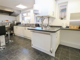 A kitchen with white cabinets black countertops two sinks stainless steel appliances and bar stools at The Burleigh in Hunstanton