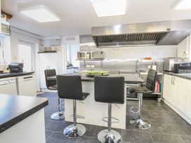 A kitchen with a central island and four black bar stools microwaves and various appliances at The Burleigh in Hunstanton