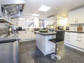 A kitchen with white cabinets black countertops a kitchen island with stools and stainless steel appliances at The Burleigh in Hunstanton