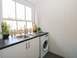 A utility room with a sink washing machine and decorative plants on the countertop at The Burleigh in Hunstanton