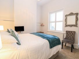 A bedroom with a bed cushions a blanket a small television a chair a mirror and a window at The Burleigh in Hunstanton