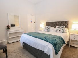 A bedroom with a bed with teal throw and patterned pillows next to bedside tables with lamps at The Burleigh in Hunstanton