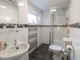 A bathroom with a sink toilet shower glass shelf towel rack and window at The Burleigh in Hunstanton