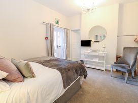 A bedroom with a bed pillows a chair a dresser with a mirror and a television at The Burleigh in Hunstanton