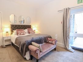 A bedroom with a bed two bedside tables lamps three mirrors and a bench at The Burleigh in Hunstanton