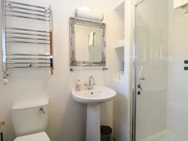 A bathroom with a toilet, pedestal sink, wall mirror, glass shower enclosure, and a heated towel rack at The Burleigh in Hunstanton