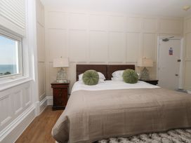 A bedroom with a bed with green round pillows two bedside tables with lamps and a window showing the sea at The Burleigh in Hunstanton