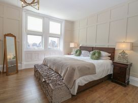 A bedroom with a large bed two round green pillows two bedside tables with lamps and a full-length mirror at The Burleigh in Hunstanton