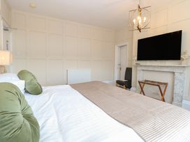 A bedroom with a bed green pillows a wall-mounted television and a fireplace at The Burleigh in Hunstanton