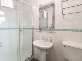 A bathroom with a shower enclosure, pedestal sink, toilet, and decorative mirror at The Burleigh in Hunstanton