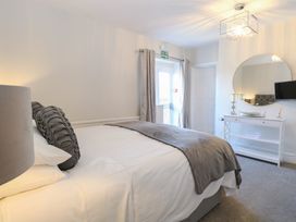 A bedroom with a bed covered with white and gray bedding a white dresser with candles and a round mirror at The Burleigh in Hunstanton
