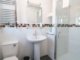 A bathroom with a toilet sink mirror and glass shower enclosure at The Burleigh in Hunstanton