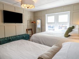 A bedroom with two beds a wall mounted television a full length mirror and a window at The Burleigh in Hunstanton