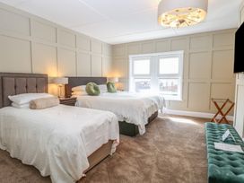 A bedroom with two beds lamps a window and a bench at The Burleigh in Hunstanton