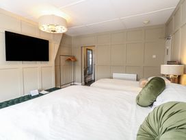 A bedroom with two beds a wall-mounted television a lamp and a clothes rack at The Burleigh in Hunstanton