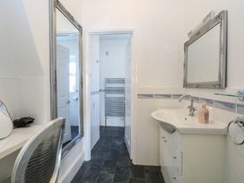 A bathroom with a sink and mirror and an adjacent room with a towel rack and tiled walls at The Burleigh in Hunstanton