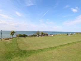 A grassy park area with people walking and benches near the sea at The Burleigh in Hunstanton