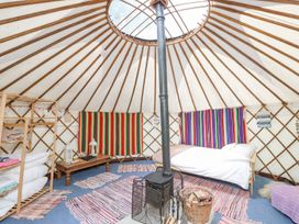 Interior of a yurt with a bed a stove rugs a wooden shelf and colorful wall hangings at Moonlight in Ventnor