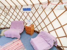 Two chairs covered with purple blankets with a wooden nightstand between them inside a yurt at Moonlight in Ventnor