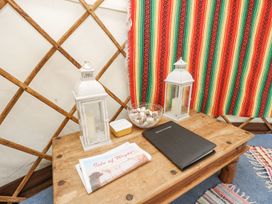 A wooden table with two white lanterns a bowl of shells a folded newspaper and a black book inside a yurt at Moonlight in Ventnor