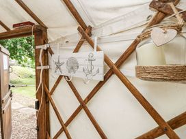 Interior of a wooden and canvas structure with hooks featuring marine designs and a hanging candle holder at Moonlight in Ventnor