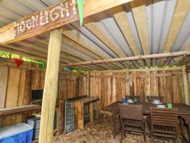 A wooden outdoor dining area with table and chairs and string lights at Moonlight in Ventnor