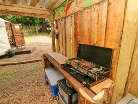 An outdoor wooden cooking area with a portable stove and storage containers next to a wooden fence at Moonlight Ventnor