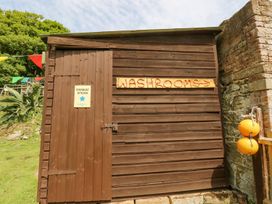 A brown wooden shed with a sign reading washrooms and a door with a sign saying stardust kitchen next to a stone wall with orange buoys attached