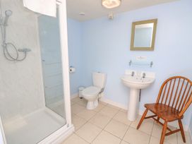 A bathroom with a shower, toilet, sink, mirror, and wooden chair at Moonlight in Ventnor