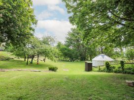 A grassy outdoor area with trees hammocks a tent and a small wooden structure at Moonlight in Ventnor