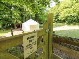 A wooden gate with a sign next to a yurt in a grassy area surrounded by trees at Moonlight in Ventnor