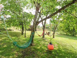 A grassy backyard with several trees hammocks and a hanging orange swing at Moonlight in Ventnor
