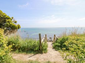 A dirt path leading to wooden steps down to a rocky coastline with green plants on both sides at Moonlight in Ventnor