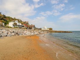 A sandy beach with stones along the shore and houses near the coastline at Moonlight in Ventnor