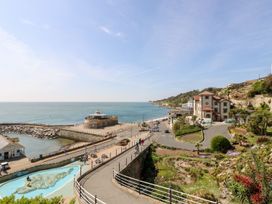 A coastal view with a paved walkway, garden area, and buildings near the sea at Moonlight in Ventnor