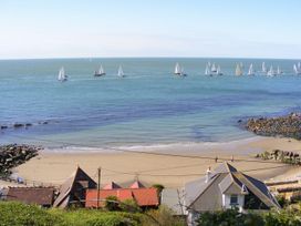 A coastal scene with a sandy beach rocky shore several houses and many sailboats on the sea at Moonlight in Ventnor