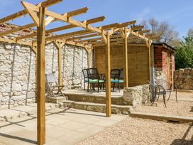 An outdoor patio area with a wooden pergola stone walls and chairs at Moonlight in Ventnor
