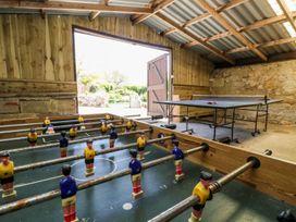 A game room with a foosball table and a ping pong table in a wooden and stone building at Moonlight in Ventnor