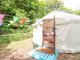 A round tent with an open door showing chairs and rugs inside and colorful bunting outside at Stardust in Ventnor