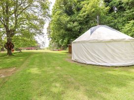 A grassy outdoor area with a large white tent a dartboard attached to a tree and tables at Stardust in Ventnor