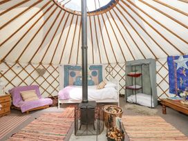 A yurt interior with a bed a stove a chair and storage unit at Stardust in Ventnor
