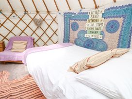 A bedroom with a bed covered in white linens and pillows a purple chair and a wall hanging with a quote at Stardust in Ventnor