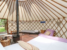 Interior of a yurt with a bed chair side table wood stove and a cot at Stardust in Ventnor