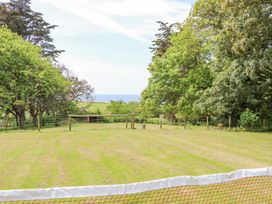 A fenced grassy field with trees and a view of the sea at Stardust in Ventnor