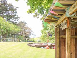 An outdoor grassy area with trees a wooden structure decorated with colorful flags and string lights at Stardust in Ventnor