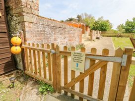 A wooden gate with a sign about yurt shower rooms beside a brick wall and lawn at Bank End Farm