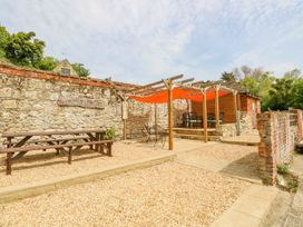 An outdoor seating area with picnic tables and chairs under orange canopies next to a stone wall at Stardust in Ventnor