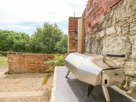 An outdoor area with a metal oven on a tiled surface next to a brick and stone wall
